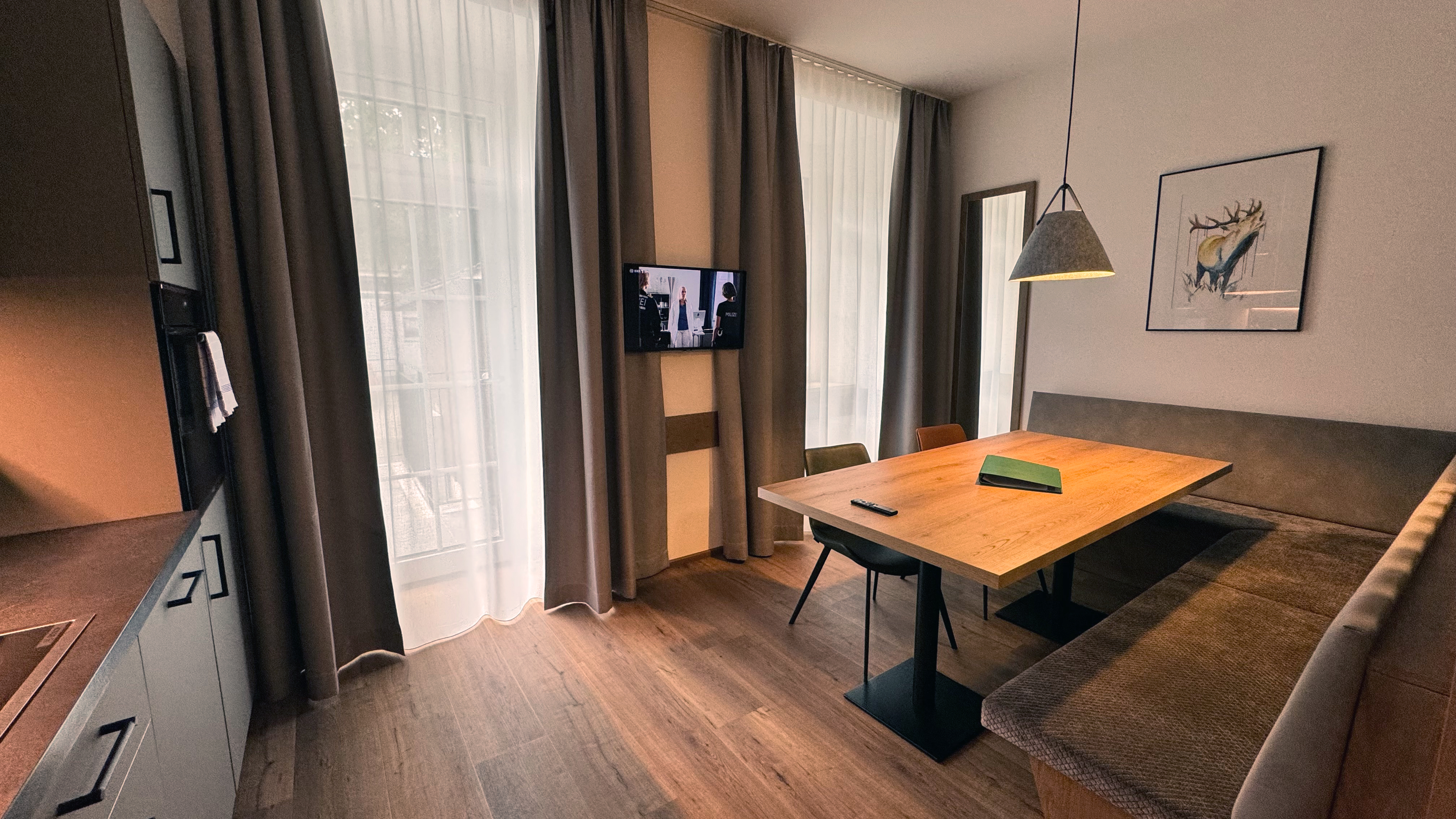 Wohnbereich der Ferienwohnung mit TV, Esstisch und Holzdetails